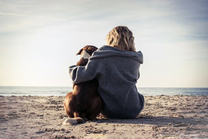 woman and dog at beach overlooking ocean